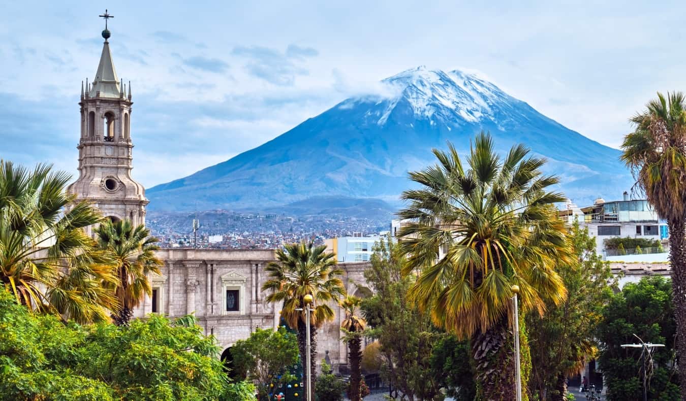 Skyline d'Arequipa au Pérou, avec une église historique et des palmiers au premier plan et un volcan en arrière-plan