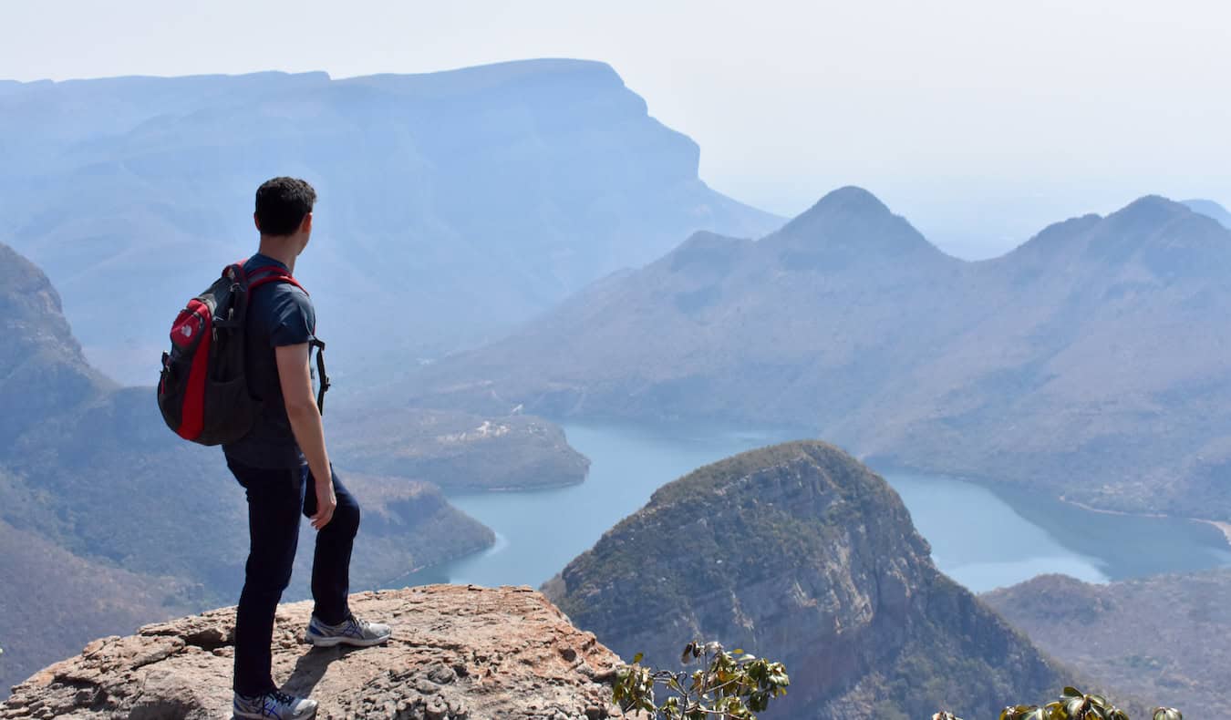 Matt nomade posant sur la crête d'un canyon imposant en Afrique du Sud avec des montagnes au loin